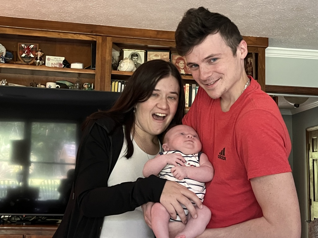 Young couple smiling with their newborn at home